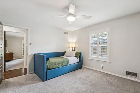 a bedroom with a large bed and a chandelier fan
