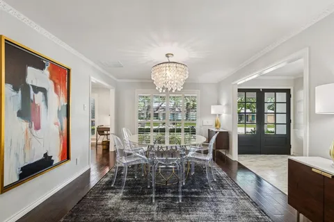 a dining room with wooden floor a chandelier a wooden table and chairs