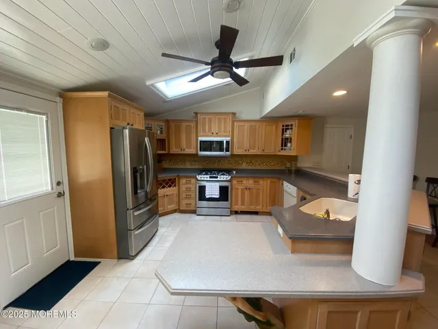 a large kitchen with stainless steel appliances granite countertop a refrigerator a stove and a sink
