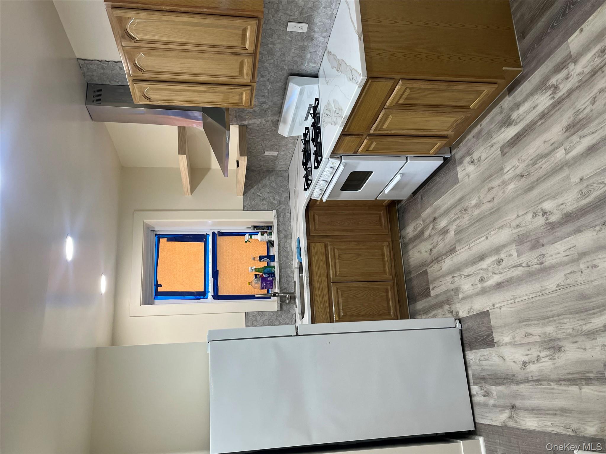 149 West Kingsbridge Road Mount Vernon, NY 10550 - Photo 17 of 25 Kitchen featuring refrigerator, white range, brown cabinetry, ventilation hood, and light wood-type flooring