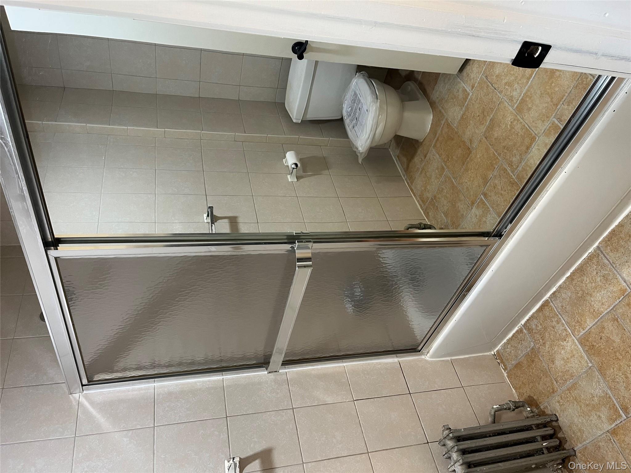 149 West Kingsbridge Road Mount Vernon, NY 10550 - Photo 18 of 25 Full bathroom featuring radiator, a shower with door, and tile walls