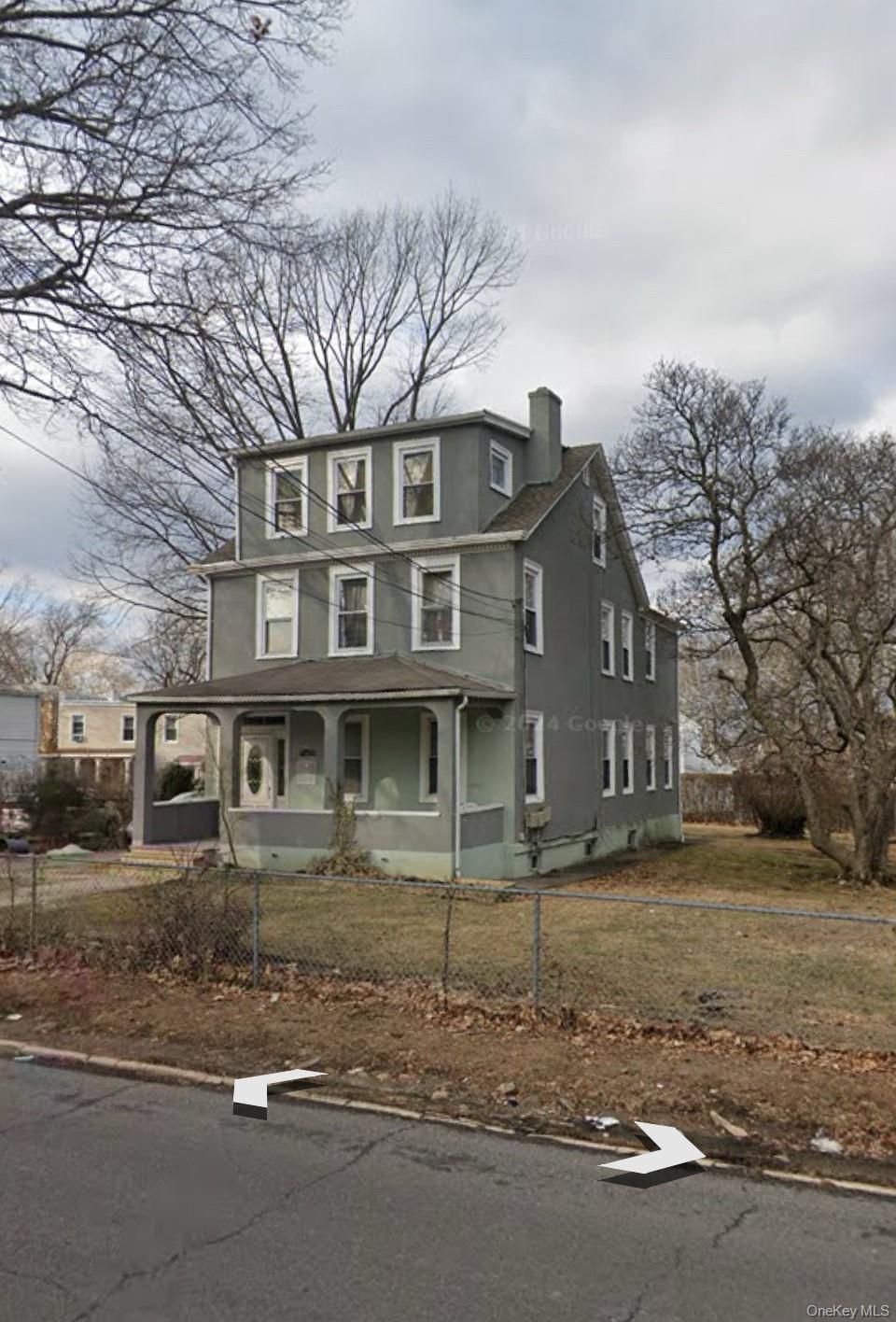 149 West Kingsbridge Road Mount Vernon, NY 10550 - Photo 25 of 25 View of front of house with stucco siding, a porch, a chimney, and a fenced front yard