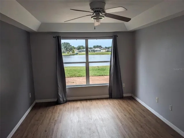 an empty room with wooden floor fan and windows