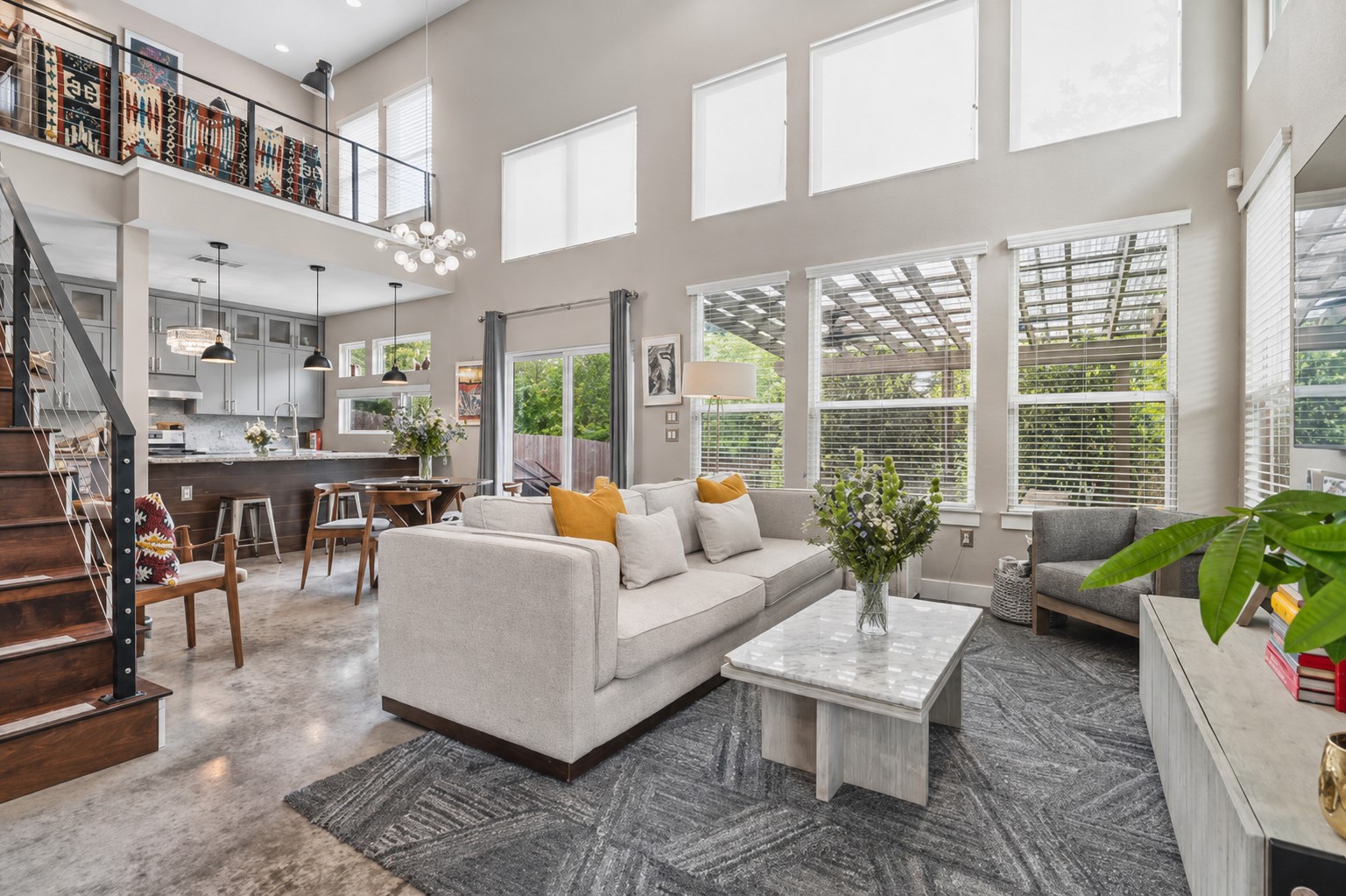 1800 Webberville Road, Unit B Austin, TX 78721 - Photo 6 of 30 Spacious open-concept living area featuring a two-story ceiling, polished concrete flooring, a kitchen with cabinetry and an island, a modern staircase with metal railings, and ample natural light from multiple windows