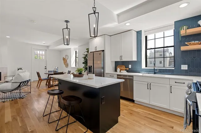 a kitchen with stainless steel appliances granite countertop a sink a stove and chairs