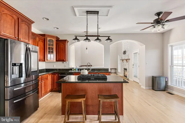 a kitchen with stainless steel appliances granite countertop a stove a refrigerator a sink a dining table and chairs with wooden floor