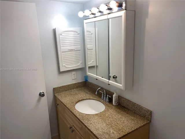 a bathroom with a granite countertop sink and a mirror
