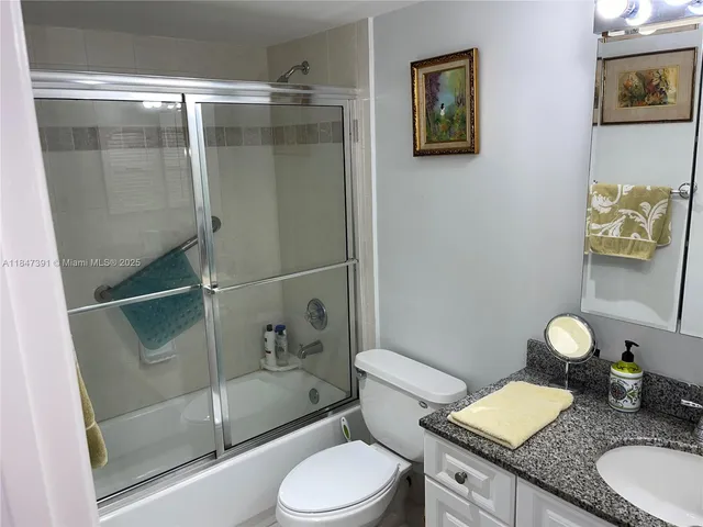 a bathroom with a granite countertop sink a mirror and shower curtain