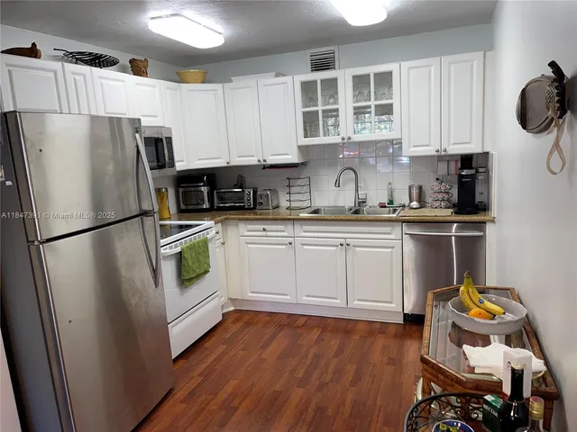 a kitchen with a refrigerator sink and white cabinets