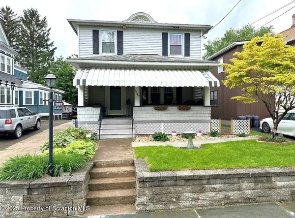 a front view of a house with a yard and potted plants