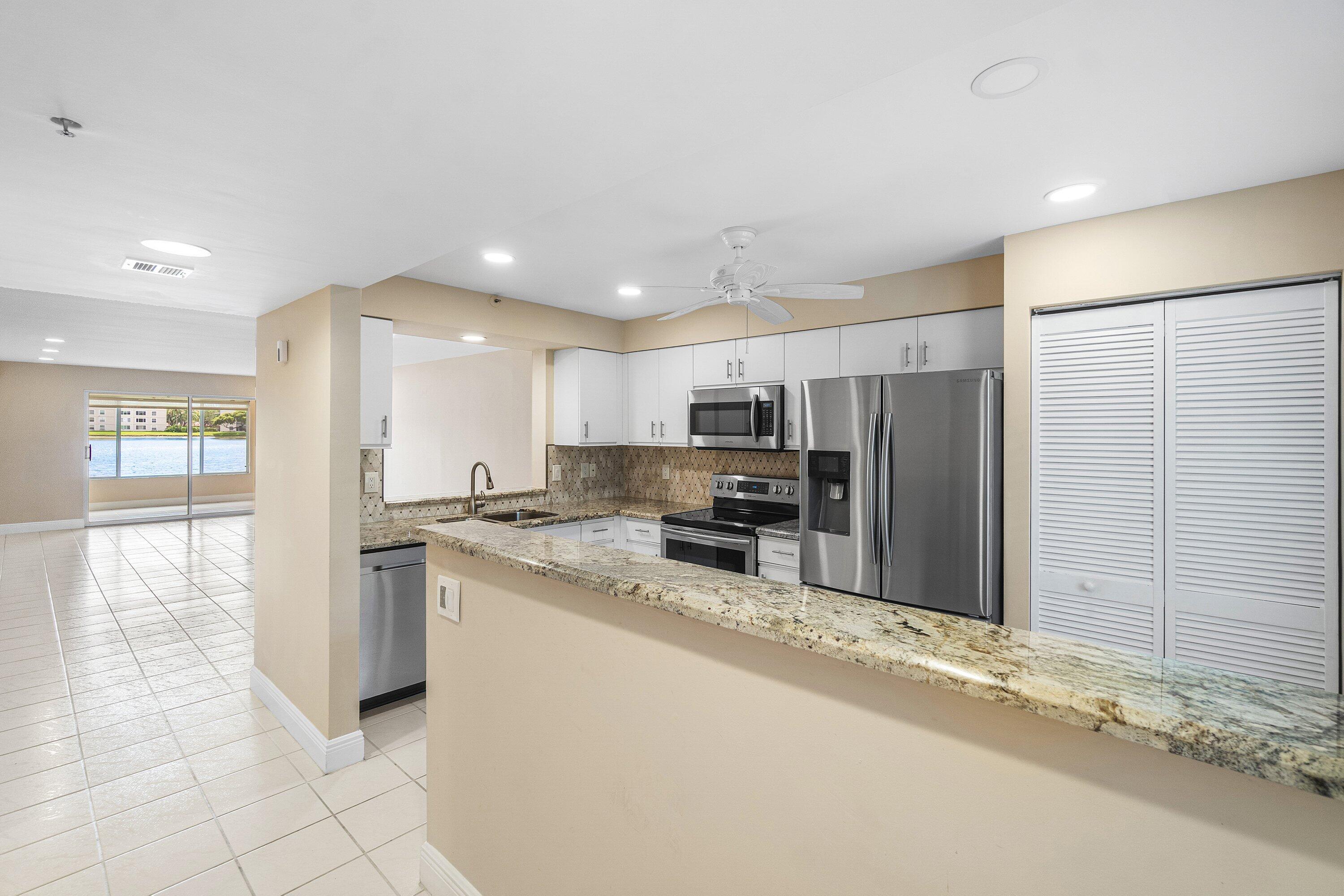 14096 Huntington Pointe Drive, Unit 106 Delray Beach, FL 33484 - Photo 17 of 47 a kitchen with stainless steel appliances granite countertop a refrigerator and a stove top oven