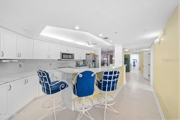 a kitchen with stainless steel appliances kitchen island granite countertop a table chairs and a refrigerator