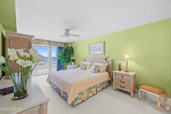 a bedroom with a bed table flowerpot and chair