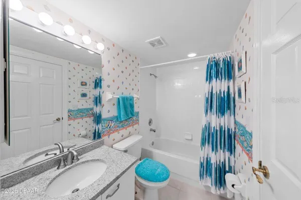 a bathroom with a granite countertop sink a toilet a mirror and shower