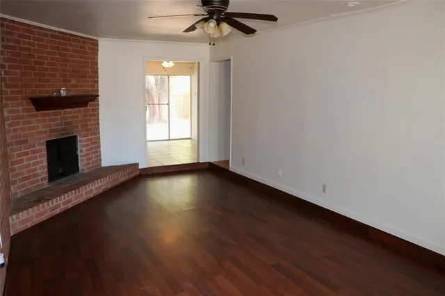 an empty room with wooden floor fireplace and windows