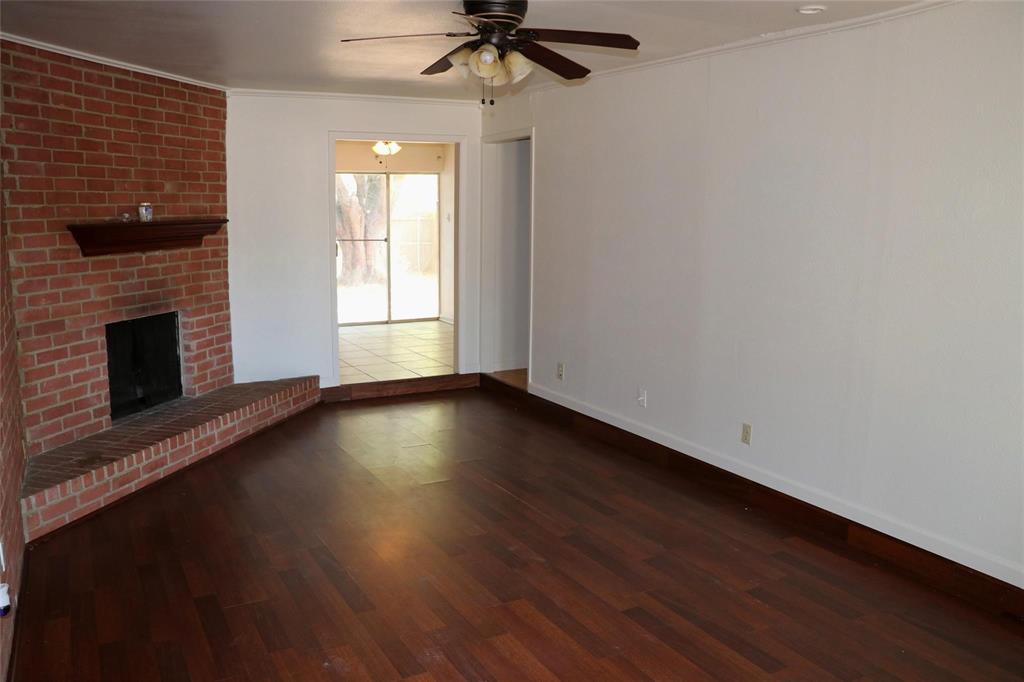 585 Manco Road Lewisville, TX 75067 - Photo 2 of 7 an empty room with wooden floor fireplace and windows