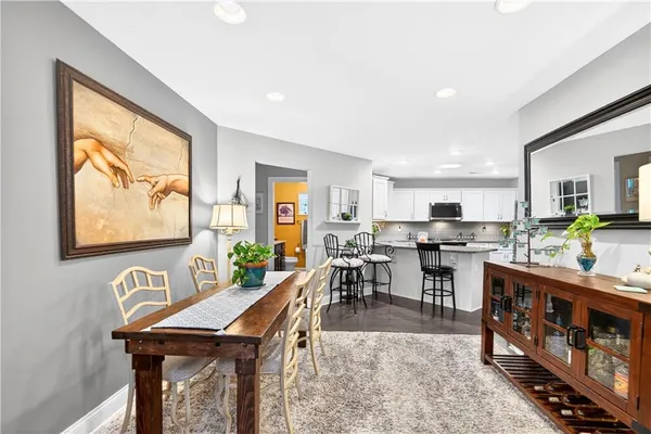 a dining hall with stainless steel appliances kitchen island granite countertop a table chairs and a refrigerator