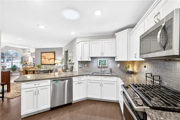 a kitchen with white cabinets appliances a sink and a window