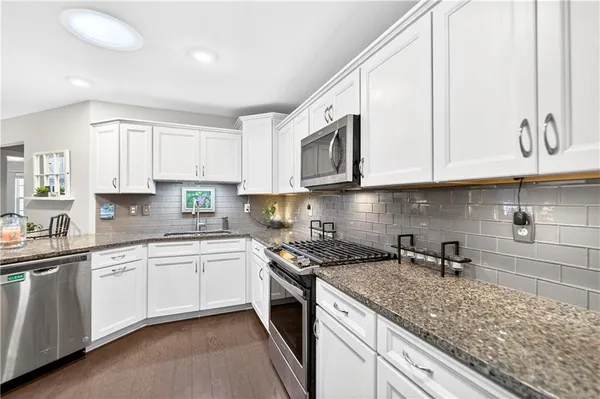 a kitchen with stainless steel appliances granite countertop white cabinets a sink and dishwasher