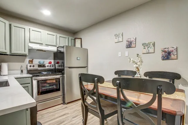 a kitchen with stainless steel appliances granite countertop a stove a refrigerator a dining table and chairs with wooden floor