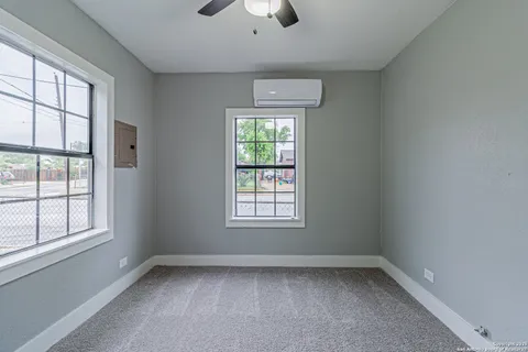 an empty room with a chandelier fan and windows