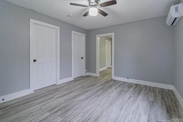 a view of empty room with wooden floor and fan