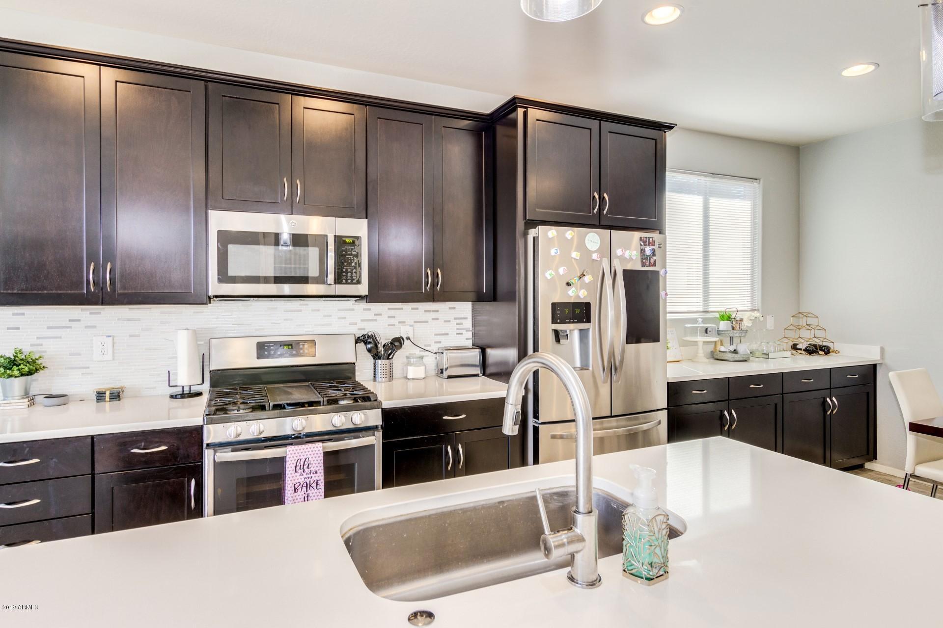 7726 West Shumway Farm Road Laveen, AZ 85339 - Photo 11 of 27 a kitchen with stainless steel appliances kitchen island granite countertop a sink stove and refrigerator