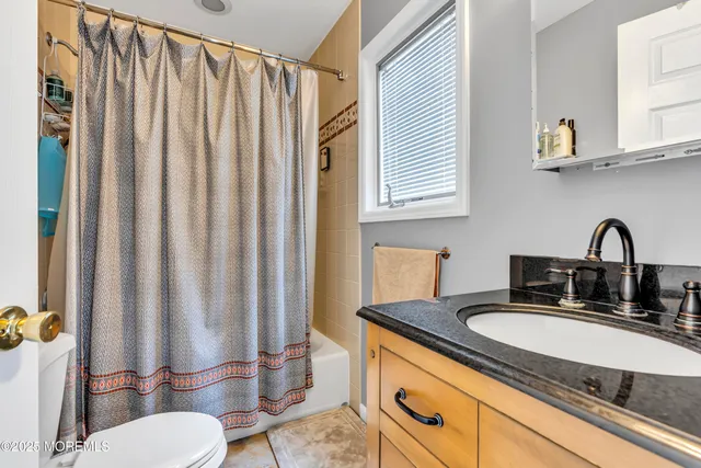 a bathroom with a granite countertop sink and a mirror with toilet