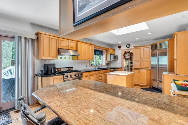 a large kitchen with stainless steel appliances granite countertop a stove refrigerator and a sink