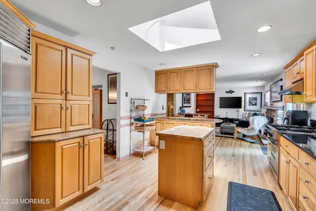 a kitchen with stainless steel appliances granite countertop a refrigerator a stove top oven a sink dishwasher and wooden cabinets with wooden floor