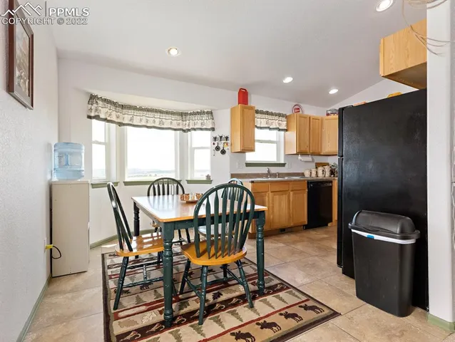 a kitchen with stainless steel appliances granite countertop a table chairs and a refrigerator