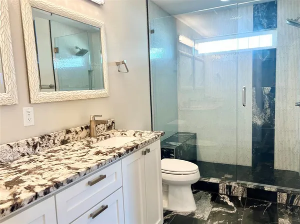 a bathroom with a granite countertop sink toilet and shower