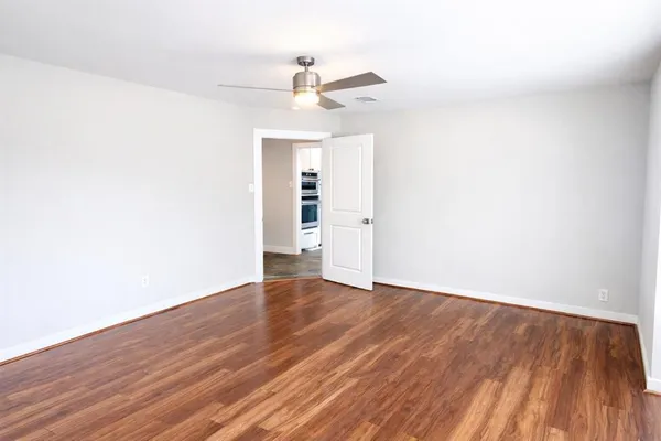 an empty room with wooden floor ceiling fan and windows
