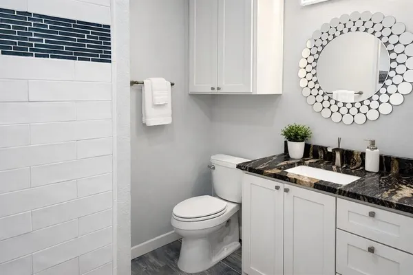 a bathroom with a granite countertop toilet sink and mirror