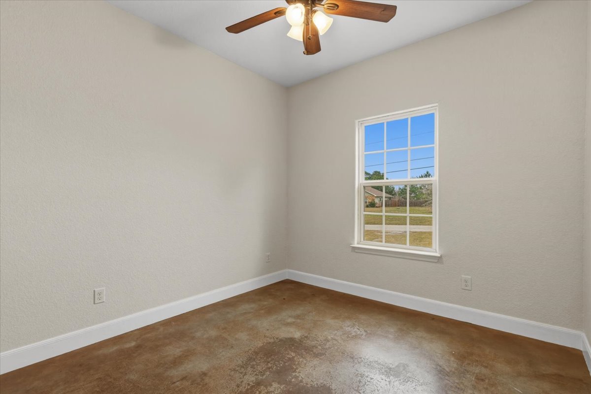 207 Cardinal Loop Paige, TX 78659 - Photo 25 of 39 an empty room with a chandelier fan and windows