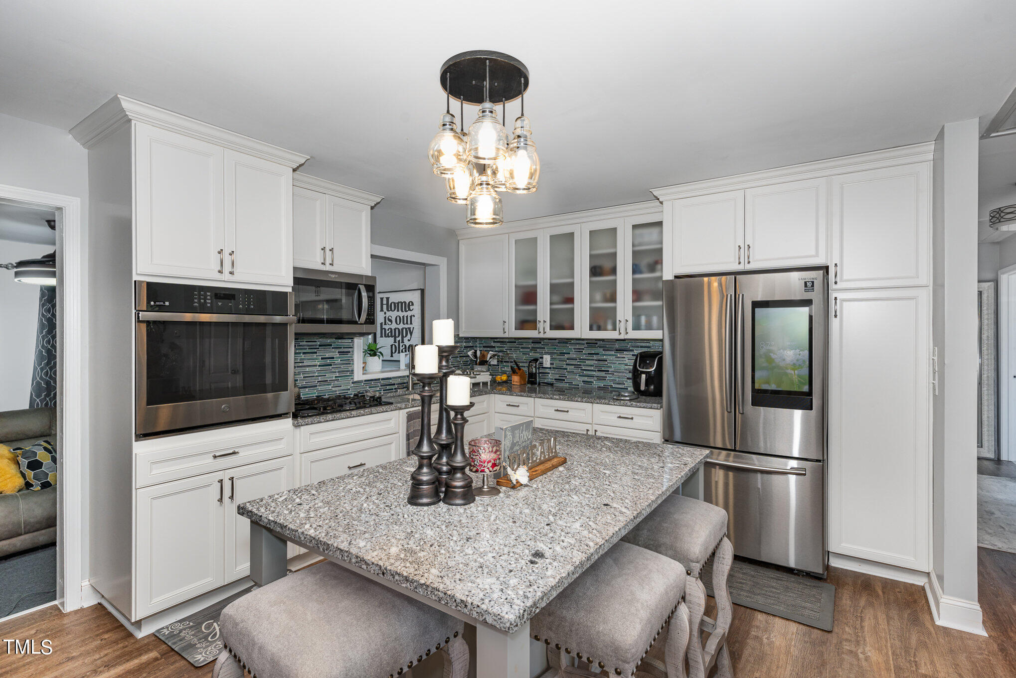 a kitchen with stainless steel appliances granite countertop a kitchen island and chairs