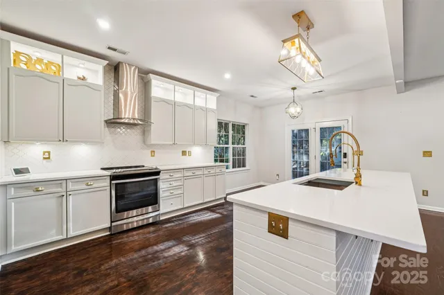a kitchen with stainless steel appliances kitchen island granite countertop a sink a stove and cabinets