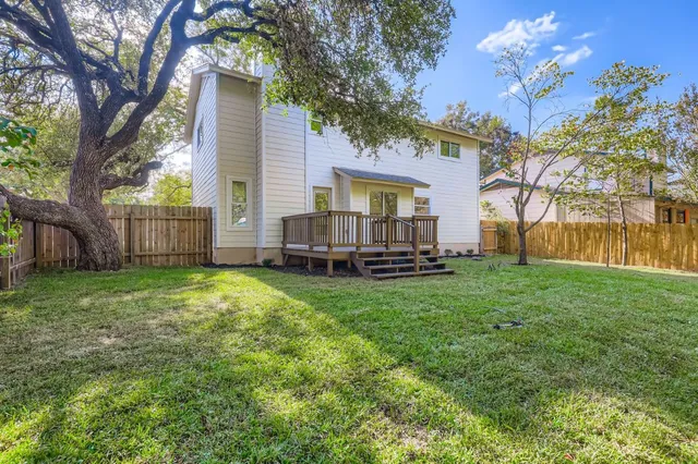 a backyard of a house with barbeque oven and large trees