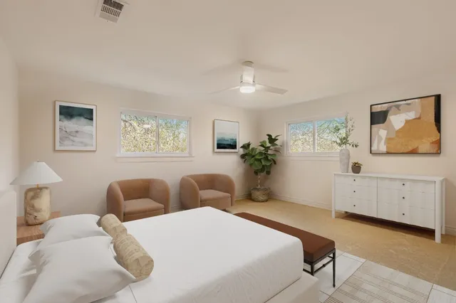 a spacious bedroom with two beds and painting on the wall