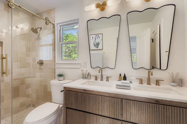 a bathroom with a double vanity sink toilet and shower