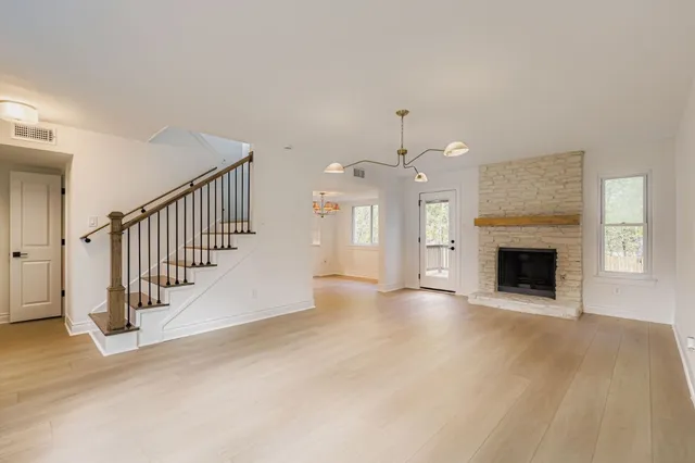 a view of an empty room with chandelier fan and fire place