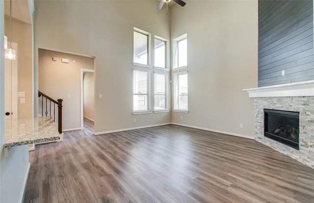 an empty room with wooden floor fireplace and windows