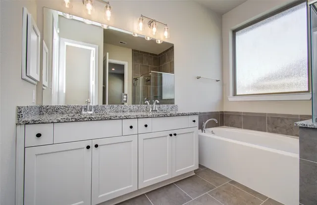 a bathroom with a granite countertop sink mirror and bathtub