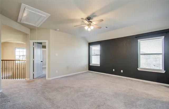 a view of an empty room with chandelier fan and windows