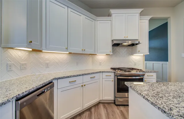 a kitchen with granite countertop a sink a stove and cabinets