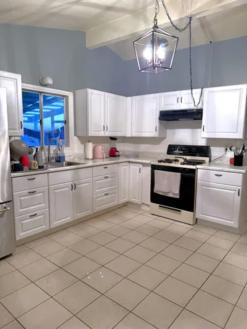 a kitchen with white cabinets a sink and white appliances