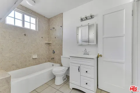 a bathroom with a toilet a sink a mirror a bathtub and window