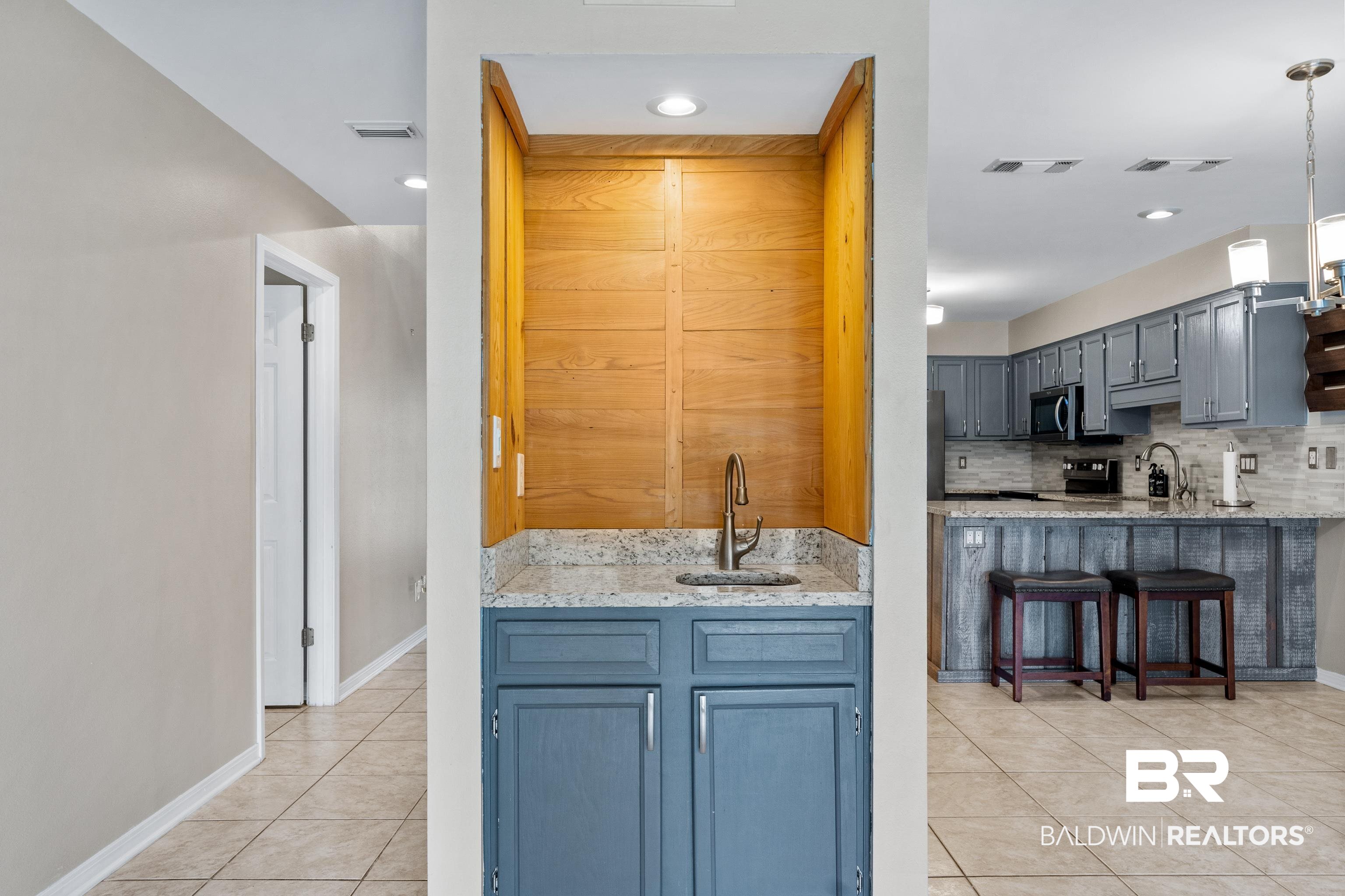 1701 Regency Road, Unit 111 Gulf Shores, AL 36542 - Photo 10 of 29 Kitchen with a kitchen breakfast bar, stainless steel appliances, backsplash, light tile patterned flooring, and decorative light fixtures