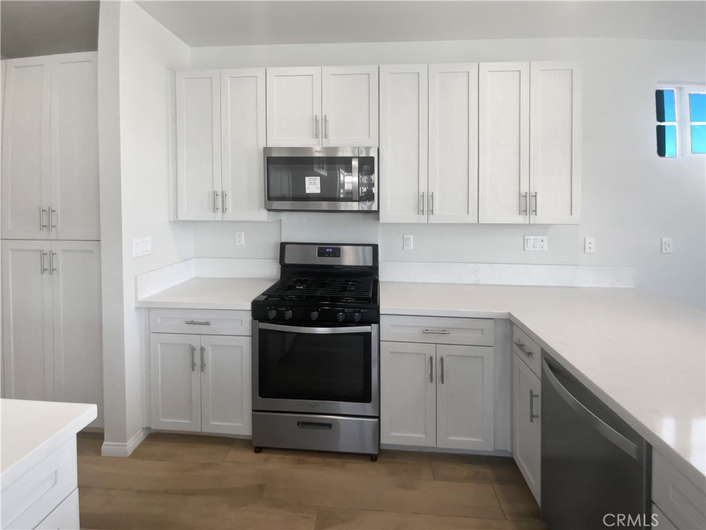 12420 Tesoro Court Grand Terrace, CA 92313 - Photo 16 of 43 a kitchen with white cabinets and stainless steel appliances