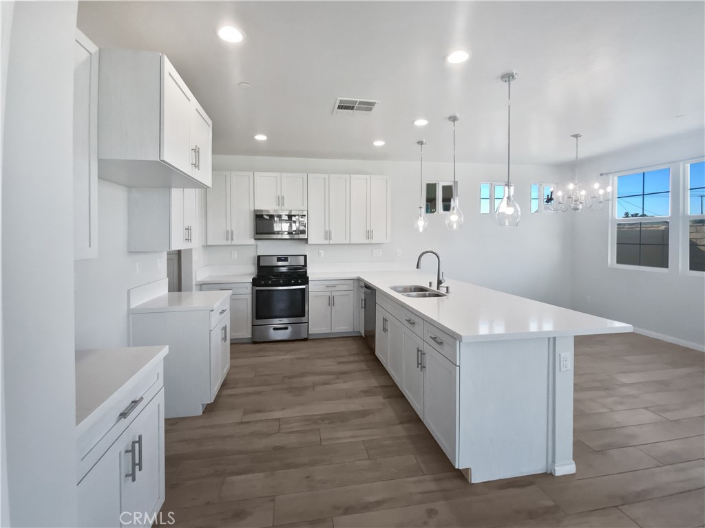 12420 Tesoro Court Grand Terrace, CA 92313 - Photo 2 of 43 a large white kitchen with stainless steel appliances sink a microwave and cabinets